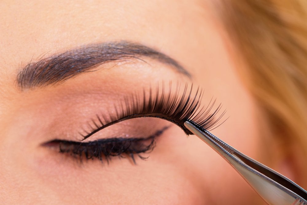 Close-up of false eyelashes being put on woman's eye | New Year’s Eve Makeup Tutorial | Gold Glitter Cut Crease With Red Lips