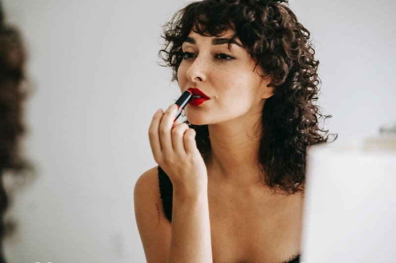 crop gentle woman making up lips in front of mirror | clear lip gloss