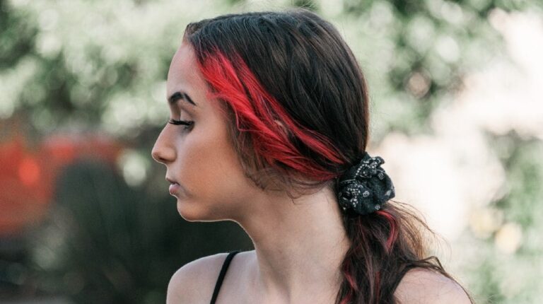 pensive woman with red hair strand | How To Create The Perfect Eyebrow Slit | Featured