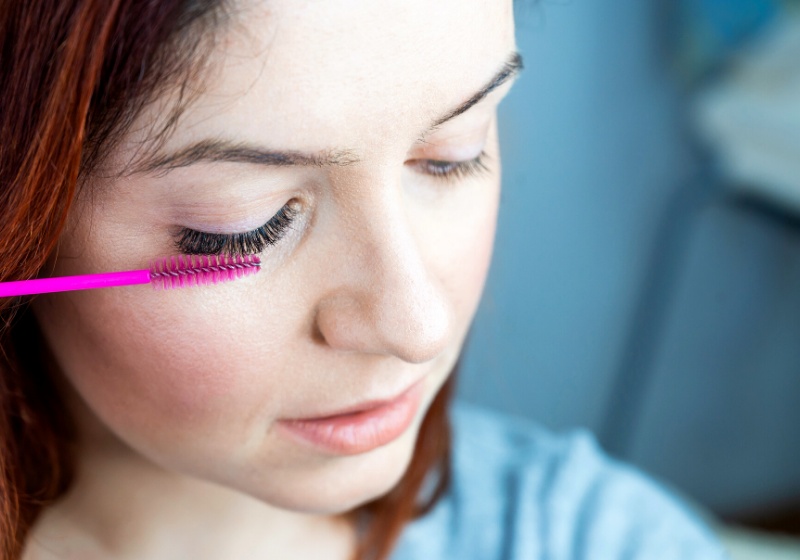 red head woman brushing her extension | how to put on false eyelashes for beginners