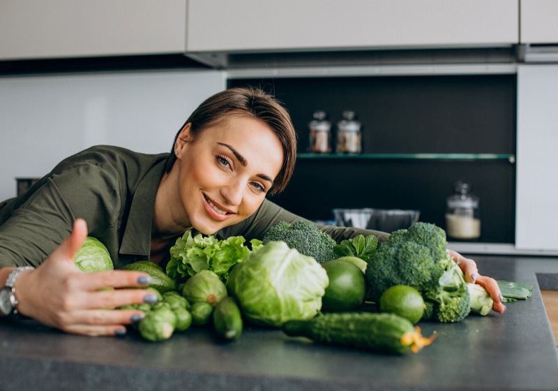 woman green vegetables kitchen | does moisturizer prevent wrinkles