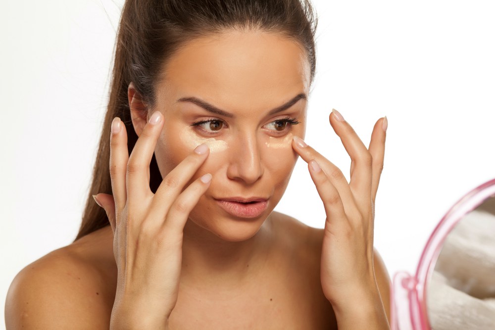 Young woman apply different shades of liquid foundation on her face | New Year’s Eve Makeup Tutorial | Gold Glitter Cut Crease With Red Lips