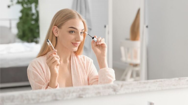 young woman applying oil onto her eyelashes | How To Grow Eyelashes Naturally In Simple Ways (or Steps) | eyelash curler | Featured